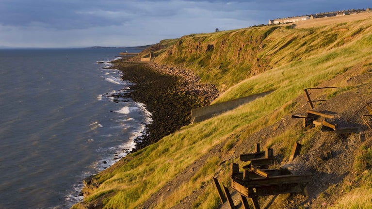 Remains of industrial workings jut out from cliffs above a grey sea on the Whitehaven Coast, Cumbria